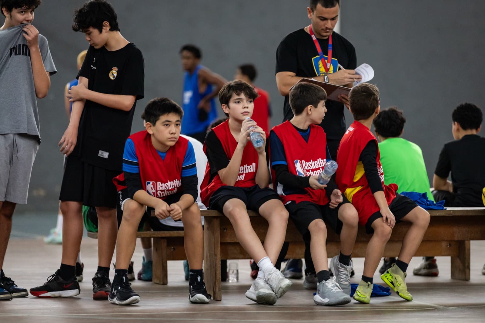 Atletas no banco se hidratando entre partidas, com a equipe por perto