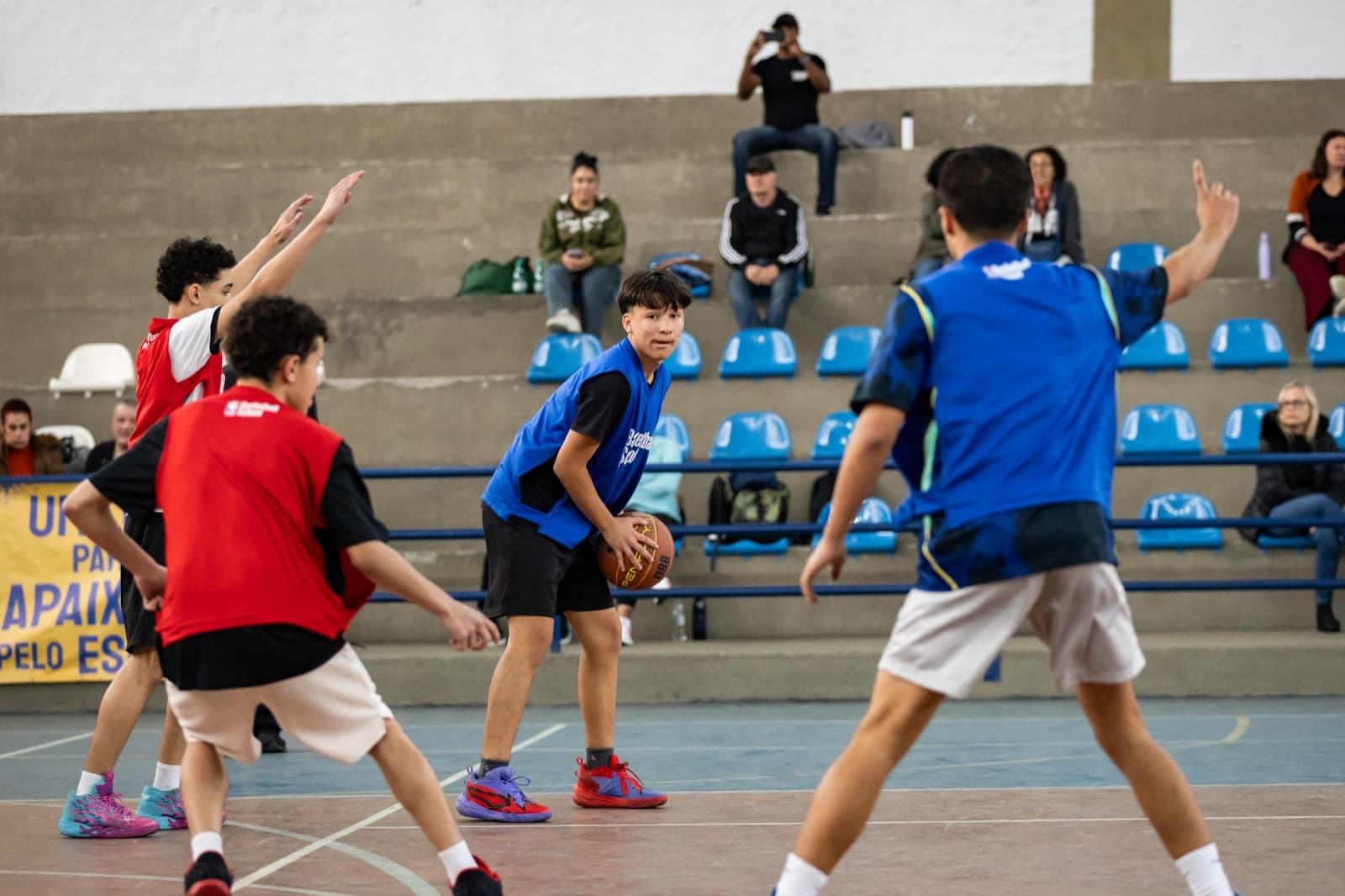Quadra em jogo com defesa montada, espaço poliesportivo ao redor