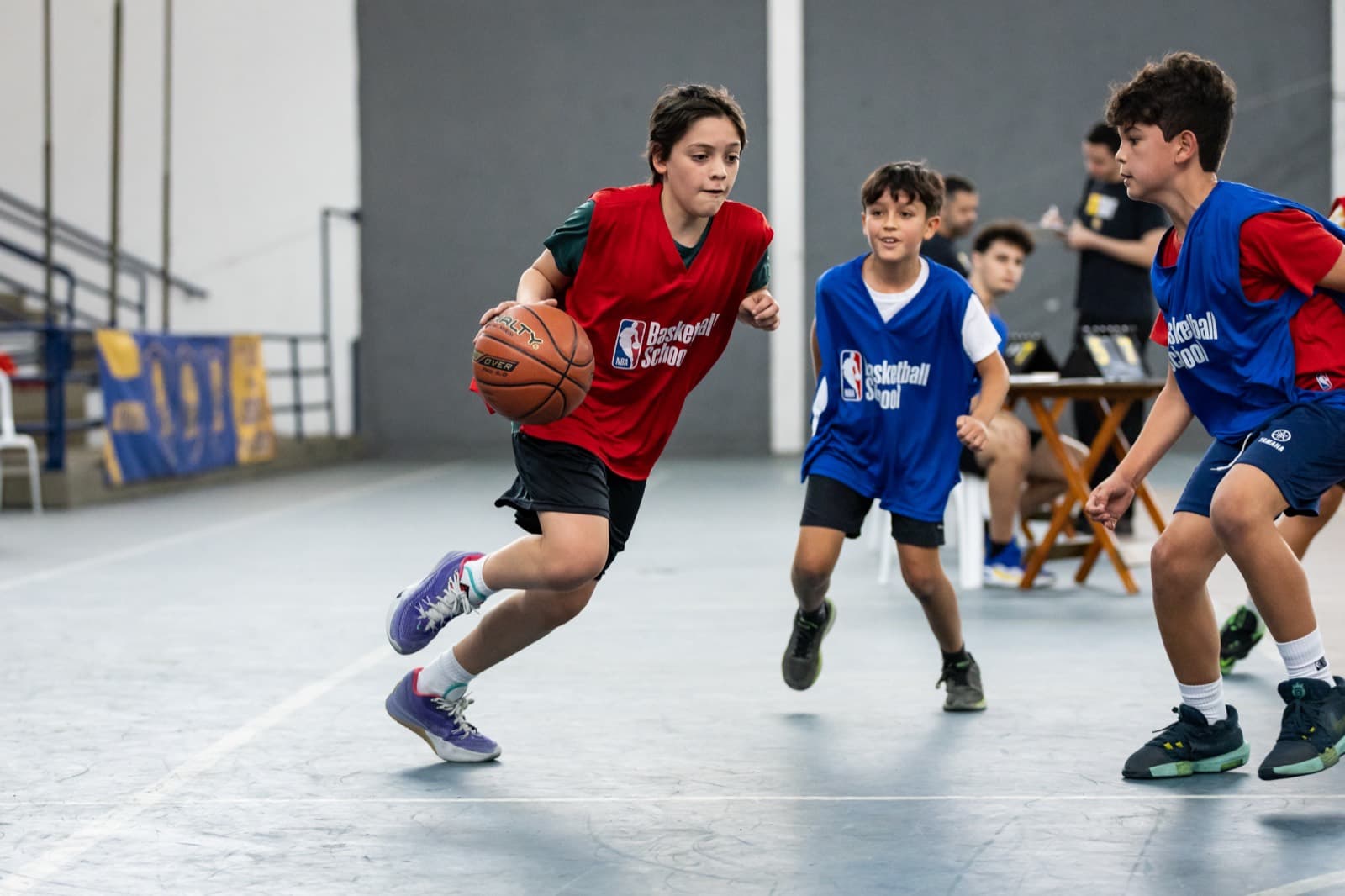 Atleta conduzindo a bola no ataque, marcado por dois adversários